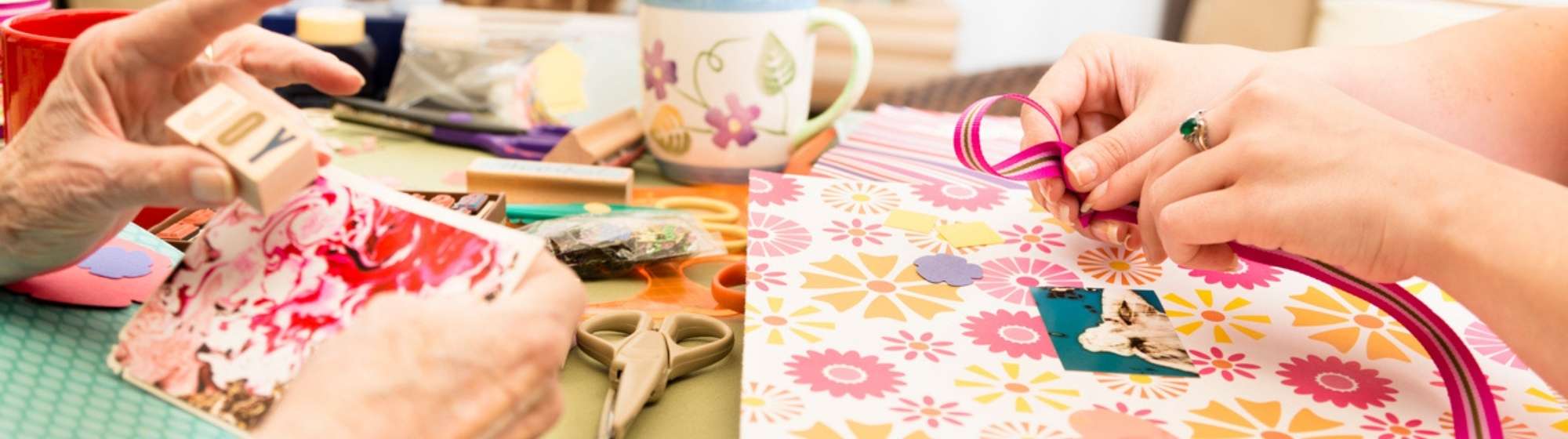 Atelier de scrapbooking avec deux personnes collant et décorant des papiers colorés.