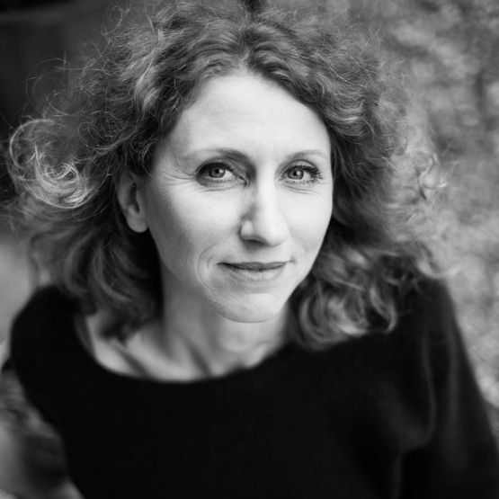 Portrait en noir et blanc d’une femme aux cheveux bouclés souriant doucement.