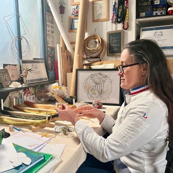 Femme dans un atelier créatif en train de modeler et dessiner des sculptures.