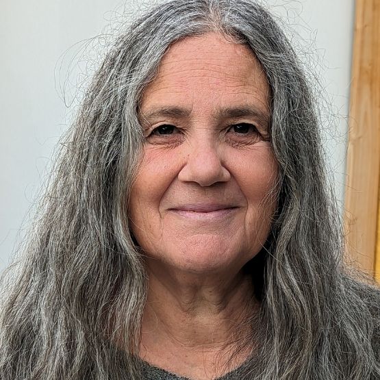 Portrait de Pascale Goldenberg, une femme avec des cheveux longs et argentés, souriante.