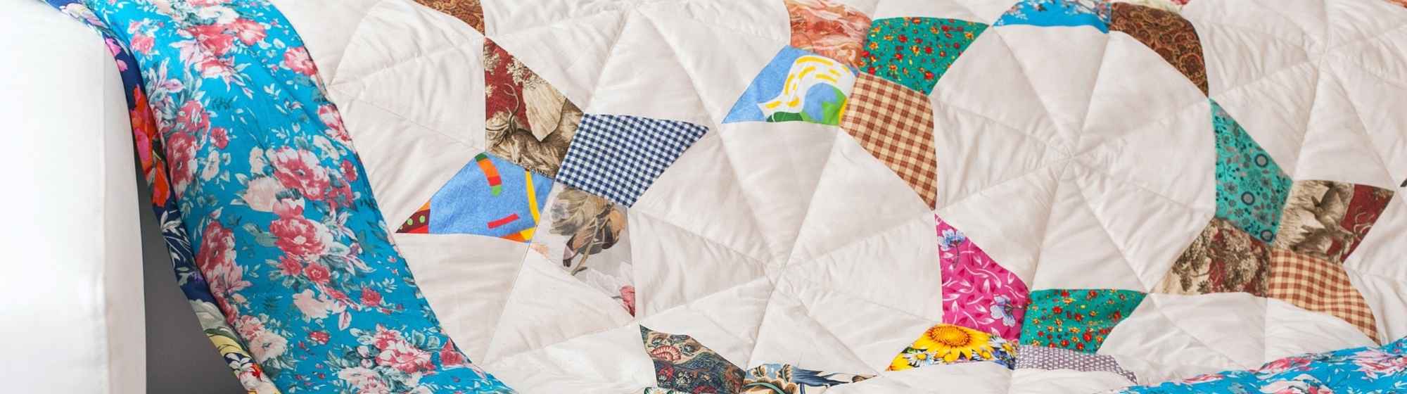 Couverture patchwork colorée posée sur un canapé blanc.