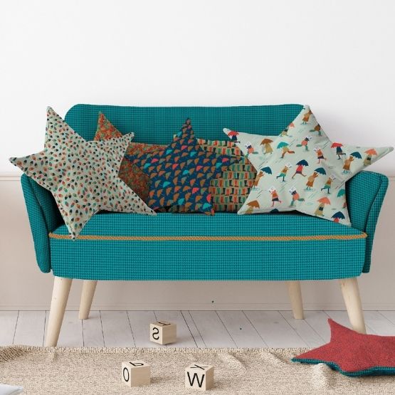 Petit canapé bleu avec coussins en forme d’étoile aux motifs colorés.