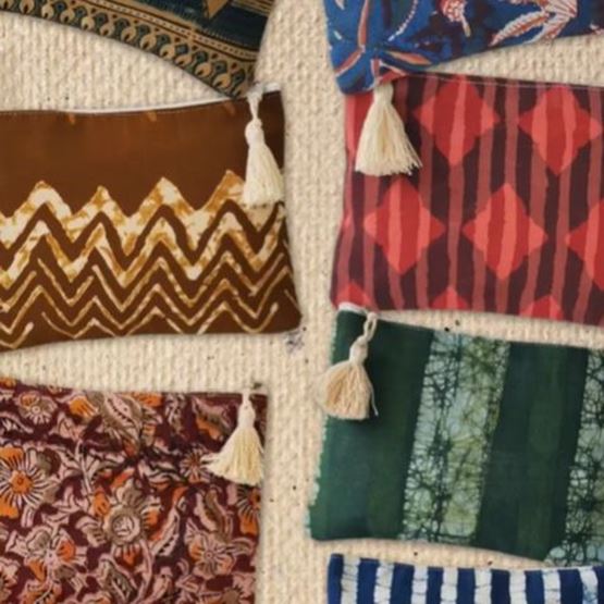 Collection de coussins aux motifs tribaux et indigo, avec des franges blanches, disposés de manière ordonnée sur un fond beige.