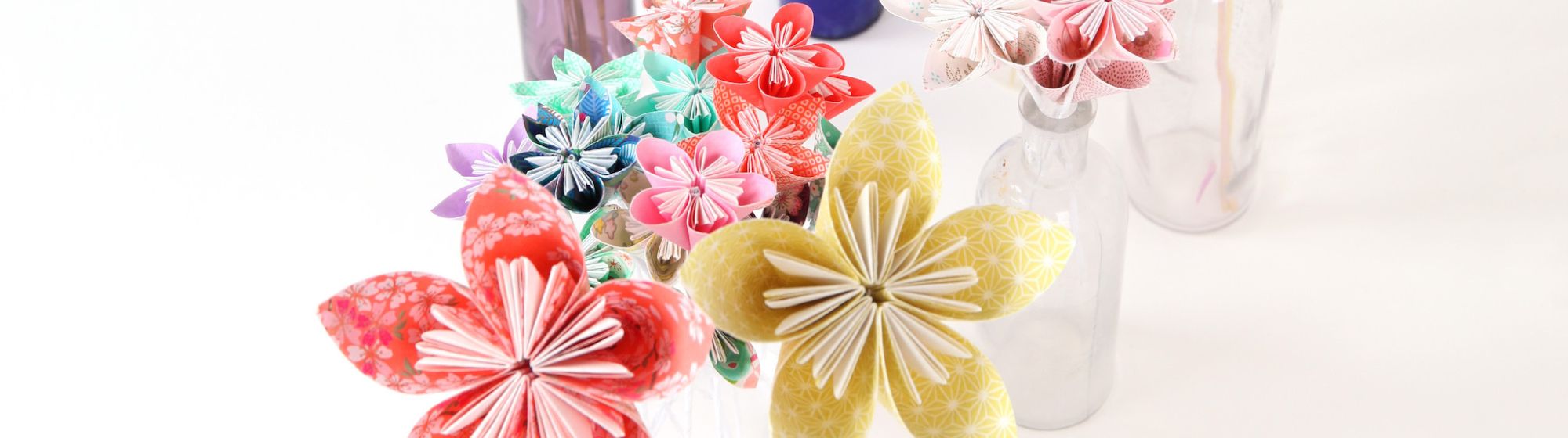 Plusieurs bouquets de fleurs colorées en origami dans des vases